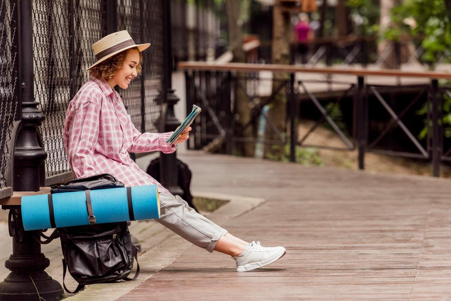 Traveler sitting outdoors with a compact backpack, embracing light packing and minimalist travel habits