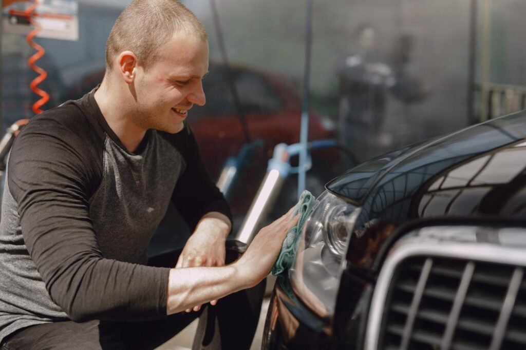 DIY car enthusiast cleaning and restoring car headlights in a home garage, highlighting hands-on vehicle maintenance and care