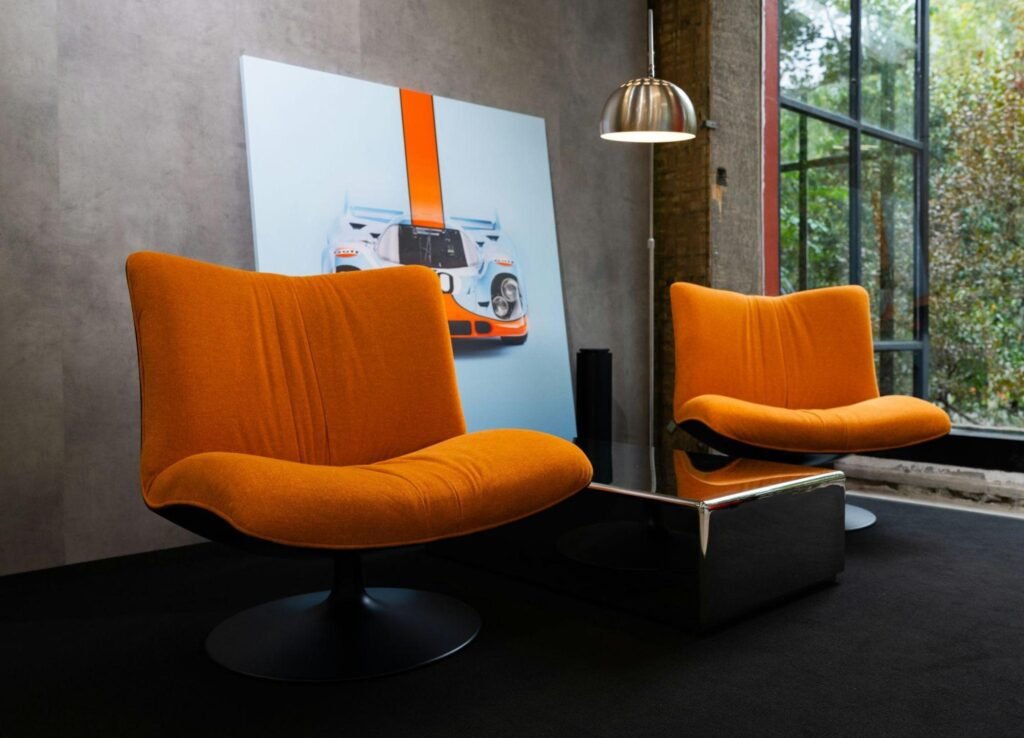 Bold orange lounge chairs paired with modern art in a richly styled maximalist living space