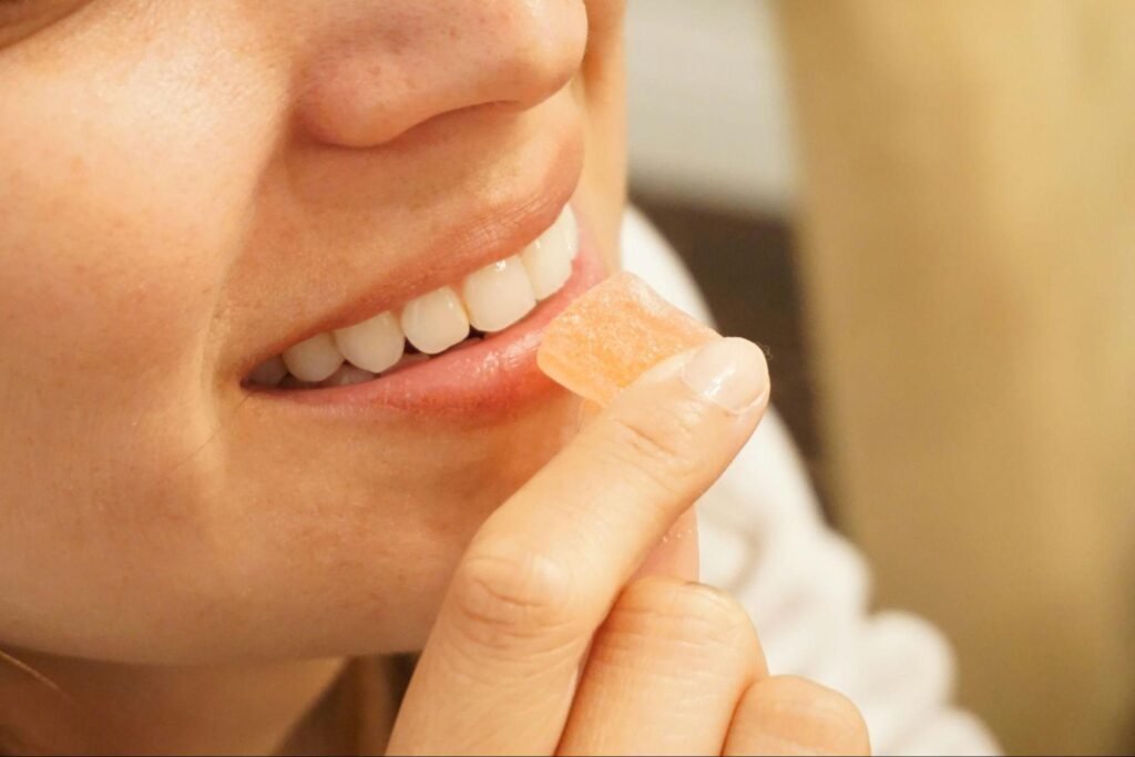 Close-up of a person holding a small gummy near their mouth, illustrating a controlled and intentional approach to relaxation